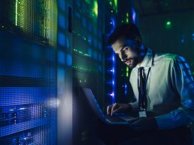 Technician examining server in big data center full of rack servers