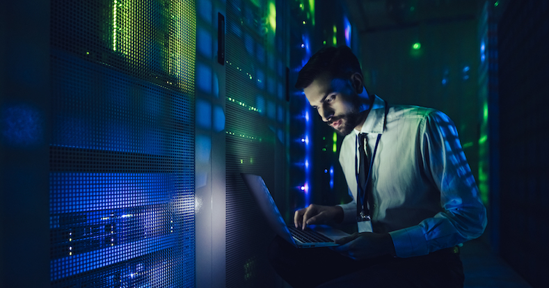Technician examining server in big data center full of rack servers