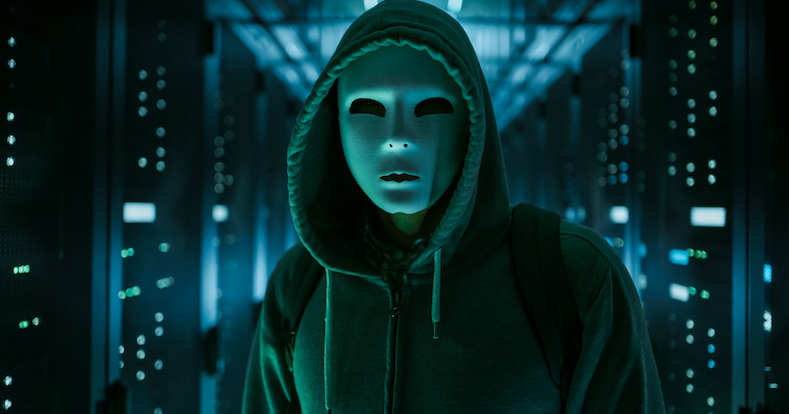 Masked Hacker in a Hoodie Standing in Corporate Data Center